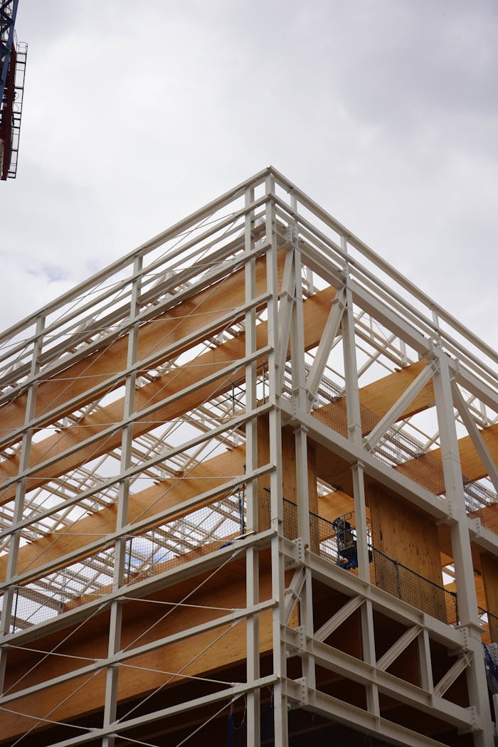 A modern building under construction with steel and wood elements, captured on a cloudy day.